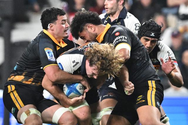 Brumbies' Rory Scott (C) is tackled by Hurricanes' defence during round 11 Super Rugby Pacific match between the Hurricanes and Brumbies at One New Zealand Stadium in Christchurch on April 25, 2026. (Photo by Sanka VIDANAGAMA / AFP)