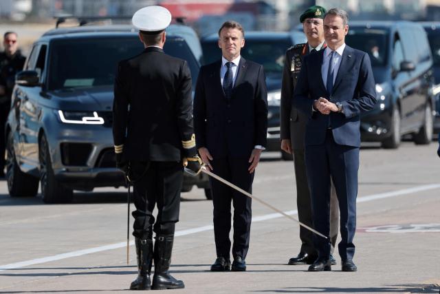 France's President Emmanuel Macron (C) and Greece's Prime Minister Kyriakos Mitsotakis take part in a welcome ceremony before a visit of Greece's new French-built frigate "Kimon" at the port of Pireus near Athens, on April 25, 2026. (Photo by Ludovic MARIN / AFP)