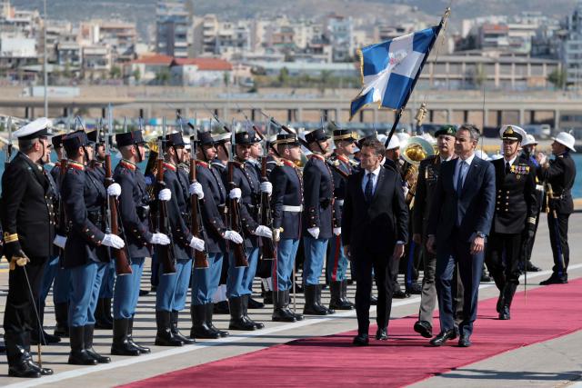 France's President Emmanuel Macron (C) and Greece's Prime Minister Kyriakos Mitsotakis take part in a welcome ceremony before a visit of Greece's new French-built frigate "Kimon" at the port of Pireus near Athens, on April 25, 2026. (Photo by Ludovic MARIN / AFP)