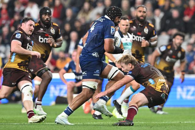 Blues' Patrick Tuipulotu (C) is tackled by Reds' Harry McLaughlin-Phillips (R) during the Super Rugby Pacific match between the Blues and Queensland Reds at One New Zealand Stadium in Christchurch on April 25, 2026. (Photo by Sanka VIDANAGAMA / AFP)