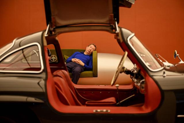 A man sleeps beside a 1954 Mercedes-Benz 300SL Coupe at the Beijing Auto Show in Beijing on April 25, 2026. (Photo by Greg Baker / AFP)