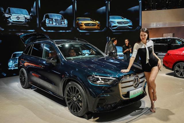 A woman poses next to a Mercedes-Benz GLC SUV at the Beijing Auto Show in Beijing on April 25, 2026. (Photo by Greg Baker / AFP)