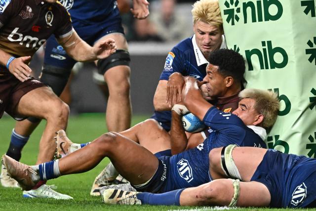Reds' Ben Volavola (C) is tackled by Blues' defence during the Super Rugby Pacific match between the Blues and Queensland Reds at One New Zealand Stadium in Christchurch on April 25, 2026. (Photo by Sanka VIDANAGAMA / AFP)
