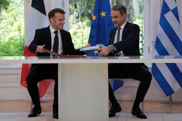 France's President Emmanuel Macron and Greece's Prime Minister Kyriakos Mitsotakis (R) sign bilateral agreements at Maximos mansion, in Athens, on April 25, 2026. The two leaders signed a text titled “Enhanced Comprehensive Strategic Partnership between Greece and France” and signed the renewal of the Strategic Relationship Agreement for cooperation in security and defense. (Photo by Ludovic MARIN / AFP)