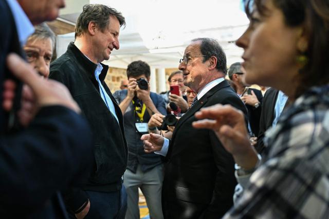 France's former President, Socialistes et Apparentes' MP Francois Hollande (Rear R) speaks with The Ecologists senator Yannick Jadot during a meeting of various figures of the left named "Printemps du souffle breton" in Liffre, western France, on April 25, 2026. (Photo by LOU BENOIST / AFP)