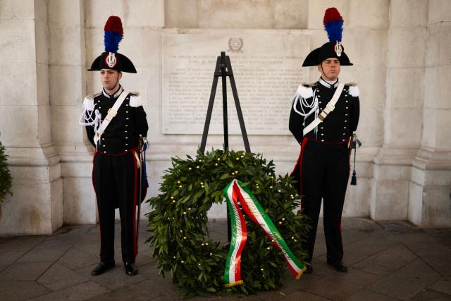 Carabinieri stand beside a commemorative wreath in front of the plaque honoring the Gold Medal awarded to the city of Genoa during a ceremony marking the 81st Liberation Day which commemorates the end of the Nazi-Fascist occupation in Italy during World War II in Genoa on April 25, 2026. (Photo by MARCO BERTORELLO / AFP)