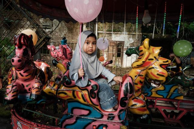 A four-year-old girl rides a makeshift carousel installed along a street in Rangkasbitung, Banten, on April 24, 2026. (Photo by YASUYOSHI CHIBA / AFP)