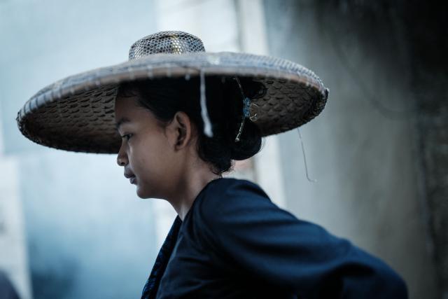 A woman of the Baduy ethnic group, known for maintaining ancestral customs and the limited use of modern technology, walks in Kanekes, Banten province on April 24, 2026. The Baduy people are an indigenous community in western Java, divided into the Inner Baduy, who wear white and follow stricter traditional customs, and the Outer Baduy, who typically wear dark clothing and have more interaction with the outside world. (Photo by YASUYOSHI CHIBA / AFP)
