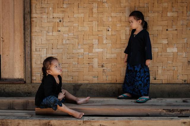 Four-year-old girls of the Baduy ethnic group, known for maintaining ancestral customs and the limited use of modern technology, play in Kanekes, Banten province on April 24, 2026. The Baduy people are an indigenous community in western Java, divided into the Inner Baduy, who wear white and follow stricter traditional customs, and the Outer Baduy, who typically wear dark clothing and have more interaction with the outside world. (Photo by YASUYOSHI CHIBA / AFP)