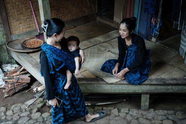 Women of the Baduy ethnic group, known for maintaining ancestral customs and the limited use of modern technology, talk in Kanekes, Banten province on April 24, 2026. The Baduy people are an indigenous community in western Java, divided into the Inner Baduy, who wear white and follow stricter traditional customs, and the Outer Baduy, who typically wear dark clothing and have more interaction with the outside world. (Photo by YASUYOSHI CHIBA / AFP)