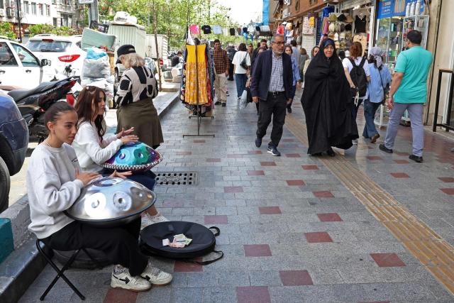 Iranian street musicians perform along a street in Tehran on April 25, 2026. (Photo by AFP) / 