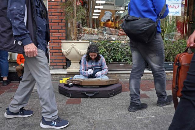 An Iranian street musician performs along a street in Tehran on April 25, 2026. (Photo by AFP) / 