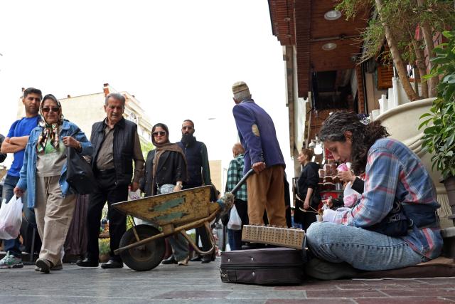An Iranian street musician performs along a street in Tehran on April 25, 2026. (Photo by AFP) / 
