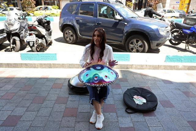 Iranian street musician Sadaf performs along a street in Tehran on April 25, 2026. (Photo by AFP) / 