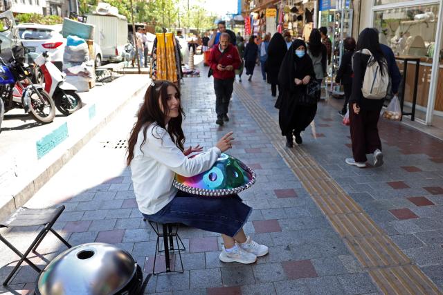Iranian street musician Sadaf performs along a street in Tehran on April 25, 2026. (Photo by AFP) / 