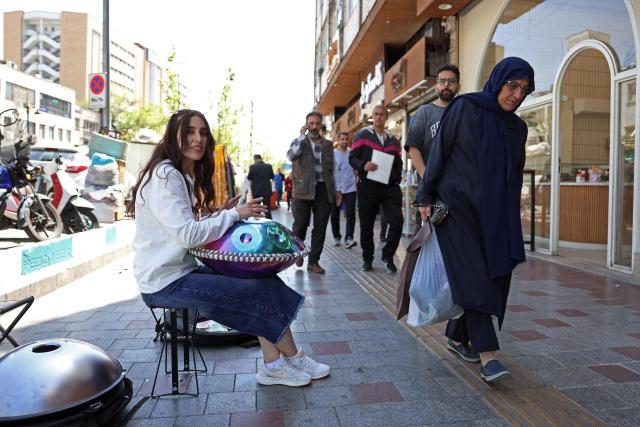 Iranian street musician Sadaf performs along a street in Tehran on April 25, 2026. (Photo by AFP) / 