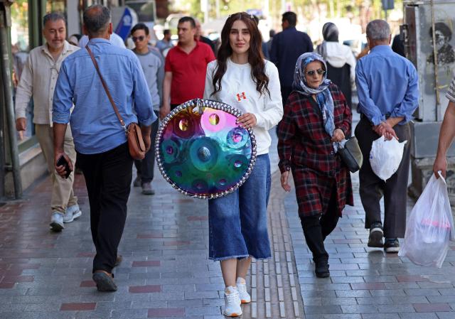 Iranian street musician Sadaf arrives to perform in a street, in Tehran on April 25, 2026. (Photo by AFP) / 