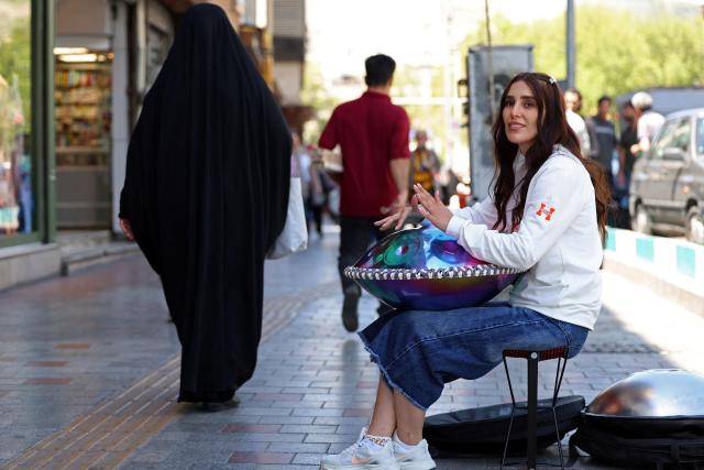 Iranian street musician Sadaf performs along a street in Tehran on April 25, 2026. (Photo by AFP) / 