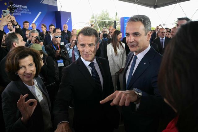 Greece's Prime Minister Kyriakos Mitsotakis (R) and France's President Emmanuel Macron (C) gesture as they attend a Franco-Greek Economic Forum at the Stavros Niarchos foundation in Athens, on April 25, 2026. The two leaders signed a text titled “Enhanced Comprehensive Strategic Partnership between Greece and France” and signed the renewal of the Strategic Relationship Agreement for cooperation in security and defense. (Photo by Angelos Tzortzinis / AFP)