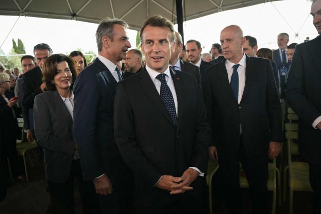 Greece's Prime Minister Kyriakos Mitsotakis (C-L) and France's President Emmanuel Macron (C) arrive to attend a Franco-Greek Economic Forum at the Stavros Niarchos foundation in Athens, on April 25, 2026. The two leaders signed a text titled “Enhanced Comprehensive Strategic Partnership between Greece and France” and signed the renewal of the Strategic Relationship Agreement for cooperation in security and defense. (Photo by Angelos Tzortzinis / AFP)