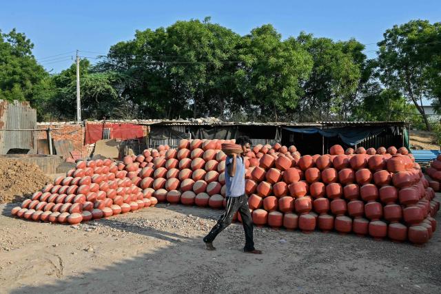 A man walks past earthen pots used to store water during summer on the outskirts of Ahmedabad on April 25, 2026. (Photo by Shammi MEHRA / AFP)