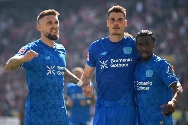 Bayer Leverkusen's Czech forward #14 Patrik Schick (C) celebrates scoring his team's first goal with Bayer Leverkusen's German midfielder #08 Robert Andrich (L) and Bayer Leverkusen's English forward #23 Nathan Tella (R) during the German first division Bundesliga football match 1 FC Cologne v Bayer 04 Leverkusen in Cologne, western Germany, on April 25, 2026. (Photo by INA FASSBENDER / AFP) / DFL REGULATIONS PROHIBIT ANY USE OF PHOTOGRAPHS AS IMAGE SEQUENCES AND/OR QUASI-VIDEO