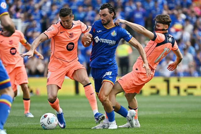 Barcelona's Polish forward #09 Robert Lewandowski (L), Getafe's Spanish defender #21 Juan Iglesias (C) and Barcelona's Spanish midfielder #16 Fermin Lopez fight for the ball during the Spanish league football match between Getafe CF and FC Barcelona at the Coliseum stadium in Getafe on April 25 , 2026. (Photo by Javier SORIANO / AFP)