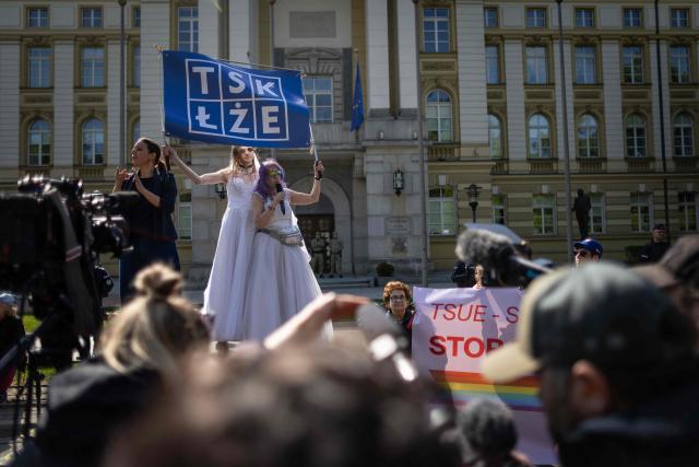 A couple holds banners reading 'Tusk is lying' as they take part in a demonstration of LGBT organisations in front of Poland's Prime Minister Chancellery building in Warsaw on April 25, 2026. The LGBT organisations point out that the Polish government has not implemented landmark rulings of the European Court of Human Rights that require Poland to recognize same-sex marriages concluded in other EU member states. (Photo by Wojtek RADWANSKI / AFP)