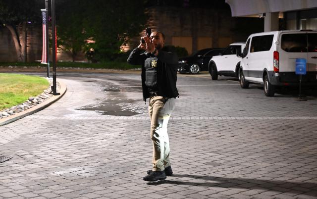 A Secret Service officer directs people outside the Washington Hilton after shots were heard during the White House Correspondents' Dinner in Washington, DC, on April 25, 2026. President Trump is attending the annual gala of the political press for the first time while in office. (Photo by Alex WROBLEWSKI / AFP)