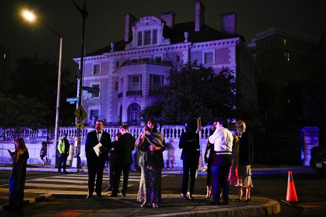Guests check their phones outside the Washington Hilton after shots were heard during the White House Correspondents' Dinner in Washington, DC, on April 25, 2026. Shots were fired as US President Donald Trump attended a press dinner in Washington on April 25 night, witnesses and AFP reporters confirmed. Loud bangs were heard and guests at the black-tie White House Correspondents' Dinner scrambled to hide under tables. Tactical teams with guns drawn took position on the stage where Trump had been sitting before he was evacuated. (Photo by Kent NISHIMURA / AFP)