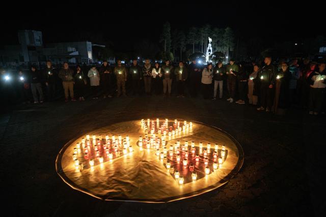 People hold candles during a commemoration ceremony marking the 40th anniversary of the explosion at the Chernobyl nuclear power plant, the worst civilian nuclear disaster in history, in front of a memorial for Chernobyl victims in the town of Slavutych on April 25, 2026, amid the Russian invasion of Ukraine. (Photo by Genya SAVILOV / AFP)