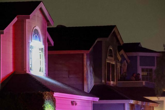 Nearby residents stand on a balcony as a spotlight is shined on a house associated with the suspected White House Correspondents Dinner shooter as an FBI tactical team arrives in armored vehicles in Torrance, California, on April 25, 2026. US President Donald Trump said April 25 he would give a press conference from the White House press briefing room, shortly after a shooting incident at a gala dinner in Washington. The press conference is set to take place shortly after 10 p.m. (0200 GMT), Trump wrote on his Truth Social platform, adding: "The First Lady, plus the Vice President, and all Cabinet members, are in perfect condition." (Photo by Patrick T. Fallon / AFP)