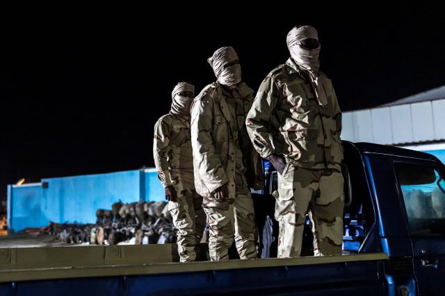 Members of the Mauritanian Coast Guard (GCM) stand on the back of a pick up truck ahead of a night patrol in Nouadhibou, on April 23, 2026. (Photo by PATRICK MEINHARDT / AFP)