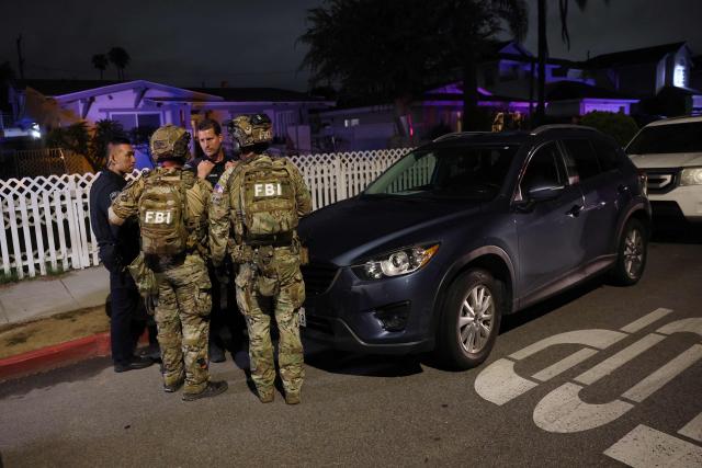 FBI tactical agents talk to Torrance police officers at the investigation scene near a house associated with the suspected White House Correspondents Dinner shooter in Torrance, California, late on April 25, 2026. US Secret Service agents bundled Donald Trump from the stage as shots rang out Saturday evening at a media gala, in what the president later described as an attack by a "would-be assassin." Armed guards opened fire at the gunman who charged through a security checkpoint just outside the ballroom of the hotel where Trump, First Lady Melania Trump, senior government officials and hundreds of other black-tie guests had gathered. (Photo by Patrick T. Fallon / AFP)
