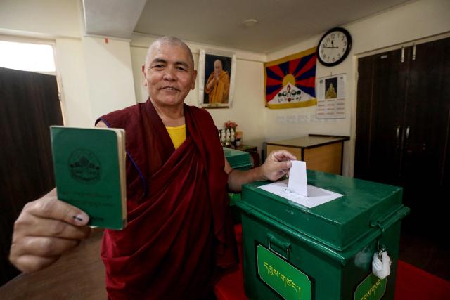 A Buddhist monk poses with his documents and inked finger while casting his ballot at a polling station in Dharamsala on April 26, 2026 during the final round of parliamentary elections held for exiled Tibetans. Tibetans outside Chinese control vote on April 26 for a government-in-exile, an election of heightened significance as they brace for an inevitable, eventual, future without their revered spiritual leader, the Dalai Lama. (Photo by Sanjay BAID / AFP)