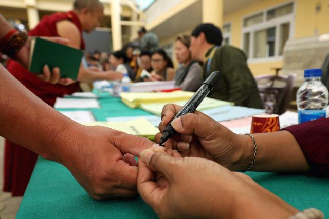 A Buddhist monk gets his finger inked before casting his ballot at a polling station in Dharamsala on April 26, 2026 during the final round of parliamentary elections held for exiled Tibetans. Tibetans outside Chinese control vote on April 26 for a government-in-exile, an election of heightened significance as they brace for an inevitable, eventual, future without their revered spiritual leader, the Dalai Lama. (Photo by Sanjay BAID / AFP)