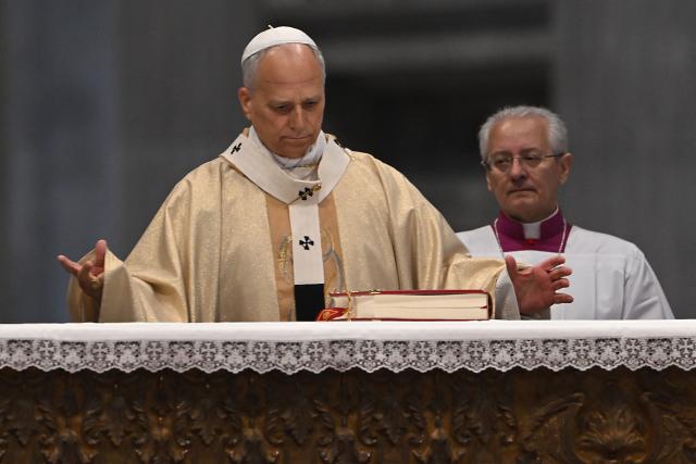 Pope Leo XIV (L) looks at a bible as he presides over the Holy Mass with Priestly Ordinations, at St Peter's Basilica in the Vatican on April 26, 2026. (Photo by Andreas SOLARO / AFP)