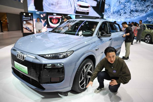 Visitors look at an Audi Q6L Sportback e-tron at the Beijing Auto Show in Beijing on April 26, 2026. (Photo by Pedro PARDO / AFP)