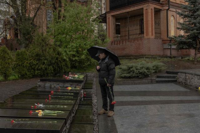 A man with an umbrella stands next to layed flowers at a memorial for the victims of Chernobyl, on the 40th anniversary of the explosion at the nuclear power plant, in Kyiv on April 26, 2026, amid the Russian invasion of Ukraine. Ukraine on April 26, 2026, marks the 40th anniversary of the explosion at the Chernobyl nuclear power plant. It comes four years into the Russian invasion that has put the plant once again under threat and raised risks of another radioactive catastrophe. The 1986 explosion at the Chernobyl nuclear power plant was the worst civilian nuclear disaster in history and changed global perceptions of nuclear energy. (Photo by Roman PILIPEY / AFP)