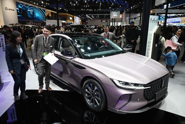 Staff walk past a Lincoln Zephyr at the Beijing Auto Show in Beijing on April 26, 2026. (Photo by GREG BAKER / AFP)