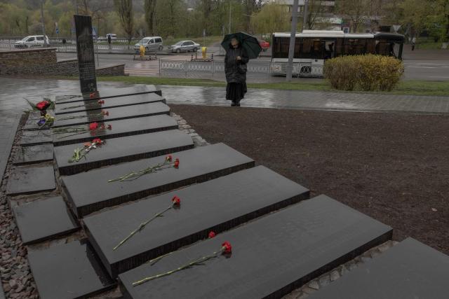 A woman with an umbrella stands next to a memorial for the victims of Chernobyl, on the 40th anniversary of the explosion at the nuclear power plant, in Kyiv on April 26, 2026, amid the Russian invasion of Ukraine. Ukraine on April 26, 2026, marks the 40th anniversary of the explosion at the Chernobyl nuclear power plant. It comes four years into the Russian invasion that has put the plant once again under threat and raised risks of another radioactive catastrophe. The 1986 explosion at the Chernobyl nuclear power plant was the worst civilian nuclear disaster in history and changed global perceptions of nuclear energy. (Photo by Roman PILIPEY / AFP)