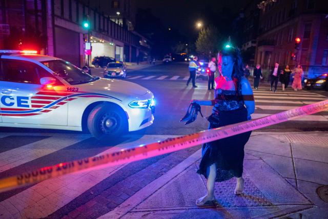 A woman leaving the Hilton Hotel walks barefoot as she crosses a police line hours after an armed gunman rushed past a security control post inside the hotel and near where  the White House Correspondents dinner was taking place at the Washington Hilton in Washington, DC, on April 25, 2025. Shots were fired as US President Donald Trump attended a media gala in Washington on Saturday night, with the gunman detained at a screening area just outside the hotel ballroom where hundreds of guests had gathered. (Photo by ROBERTO SCHMIDT / AFP)