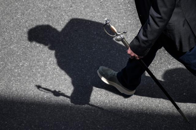 A citizen holds his sword as he walks to attend the Landsgemeinde, a traditional public, non-secret ballot conducted by majority rule, in Appenzell, eastern Switzerland, on April 26, 2026, where historically the only proof of citizenship required for men to enter the voting area was the display of a ceremonial sword or Swiss military sidearm. The open-air gathering, held annually, allows eligible citizens to decide cantonal laws and policies directly, preserving one of Switzerlands oldest forms of direct democracy. (Photo by Fabrice COFFRINI / AFP)