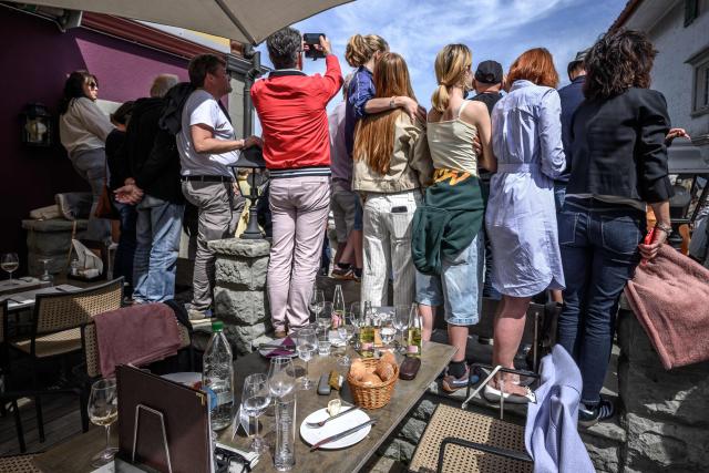 Visitors stand on a restaurant terrace to watch the parade ahead of the Landsgemeinde, a traditional public, non-secret ballot conducted by majority rule, in Appenzell, eastern Switzerland, on April 26, 2026. The open-air gathering, held annually, allows eligible citizens to decide cantonal laws and policies directly, preserving one of Switzerland’s oldest forms of direct democracy. (Photo by Fabrice COFFRINI / AFP)