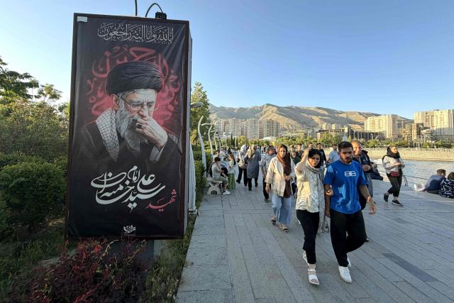 A banner reading “Martyr Ayatollah Ali Khamenei” is displayed along the walkway at Chitgar Lake, an artificial recreational lake and park officially known as the Lake of the Martyrs of the Persian Gulf, in northwestern Tehran on April 26, 2026. Iran's foreign minister returned to Islamabad, Pakistan, for more consultations on April 26, as international mediators tried to keep peace talks on track despite the US President calling off his envoys' planned trip. (Photo by ATTA KENARE / AFP) / 