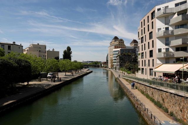 Pedestrians walk along the Canal de l'Ourcq and past the Grands Moulins de Pantin in Pantin, suburb of Paris on April 26, 2026. (Photo by Charlotte SIEMON / AFP)