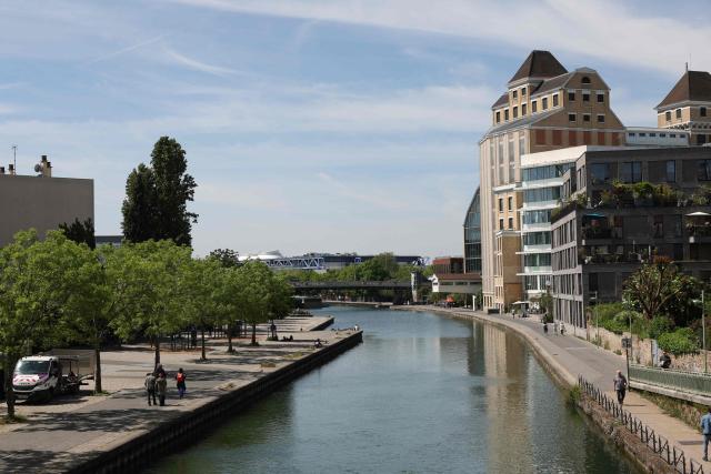 Pedestrians walk along the Canal de l'Ourcq and past the Grands Moulins de Pantin in Pantin, suburb of Paris on April 26, 2026. (Photo by Charlotte SIEMON / AFP)
