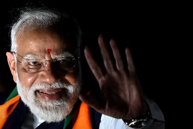 India's Prime Minister Narendra Modi greets his supporters during a roadshow in Kolkata on April 26, 2026 ahead of the second phase of the West Bengal Legislative Assembly elections. (Photo by Dibyangshu SARKAR / AFP) / ALTERNATE CROP
