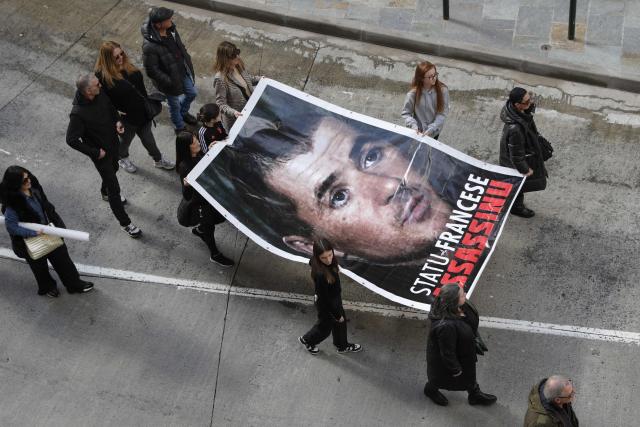 (FILES) People hold a giant picture of late Corsican nationalist Yvan Colonna during a demonstration for the rights of Corsican people and marking the second anniversary of the death of jailed Corsican nationalist Yvan Colonna in Bastia on March 2, 2024 on the French Mediterranean island of Corsica. Two investigating judges have ordered that the radicalized prisoner Franck Elong Abé will be tried for murder in connection with a terrorist enterprise after fatally attacking the Corsican activist Yvan Colonna in 2022, AFP learned on April 26, 2026 from a source close to the case. (Photo by Pascal POCHARD-CASABIANCA / AFP)