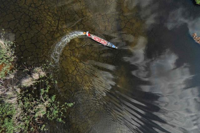 An aerial photograph of a local fishing boat in the Iraqi Hawizeh Marsh in Maysan province, southern Iraq, after water returned due to rainfall following a long period of drought on April 26, 2026. Hawizeh is a transboundary marsh shared by Iraq and Iran. (Photo by Hussein FALEH / AFP)